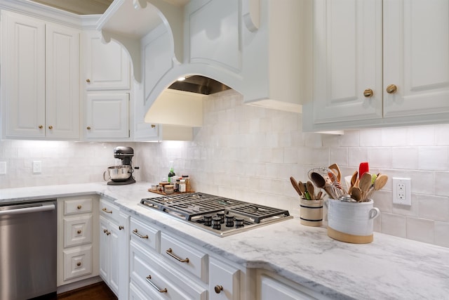kitchen featuring appliances with stainless steel finishes, decorative backsplash, light stone counters, and white cabinetry