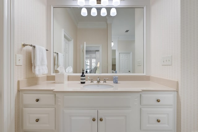 bathroom with crown molding, wallpapered walls, and vanity