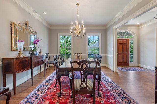 dining room featuring wood finished floors, baseboards, ornamental molding, and a notable chandelier