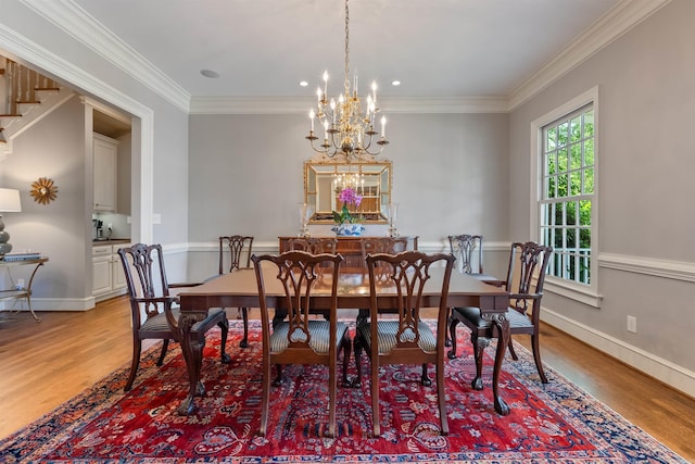 dining space featuring light wood finished floors, crown molding, and a chandelier