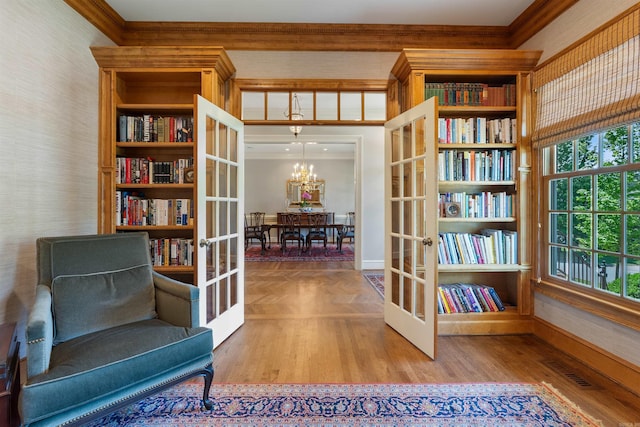 living area with wood finished floors, french doors, visible vents, baseboards, and ornamental molding