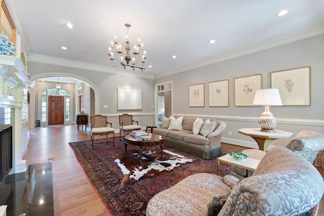living room featuring an inviting chandelier, crown molding, baseboards, arched walkways, and recessed lighting