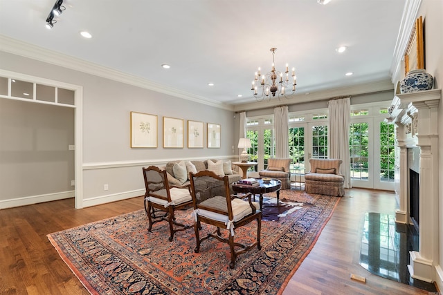 living area featuring a fireplace, a chandelier, crown molding, and wood finished floors