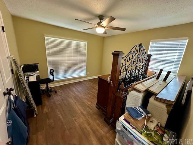 office featuring ceiling fan, a textured ceiling, baseboards, and dark wood-style floors