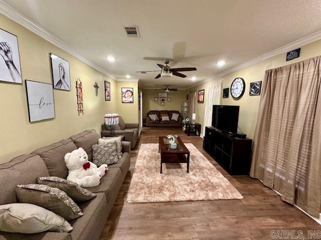 living room with wood finished floors, visible vents, recessed lighting, crown molding, and ceiling fan