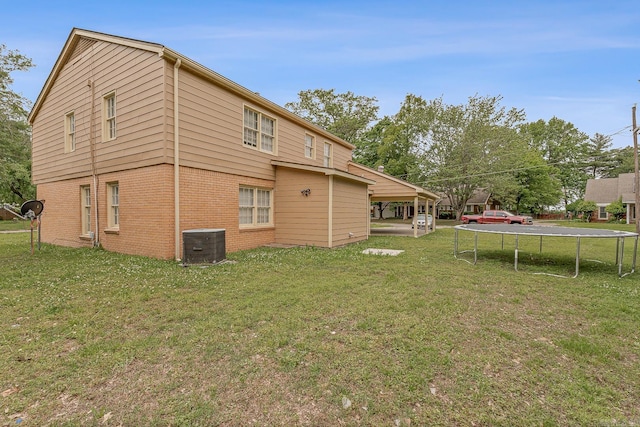 720 N 18th St, Blytheville, AR 72315 - back of house featuring a yard, a trampoline, brick siding, and central AC