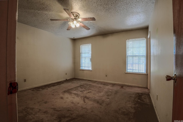 carpeted spare room featuring a textured ceiling, healthy amount of natural light, ceiling fan, and baseboards