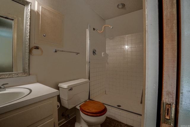 bathroom with toilet, tiled shower, and vanity