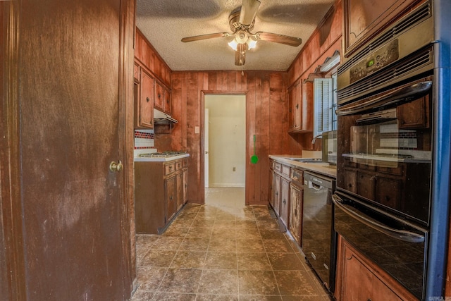 kitchen featuring black appliances, ceiling fan, a warming drawer, wooden walls, and a textured ceiling