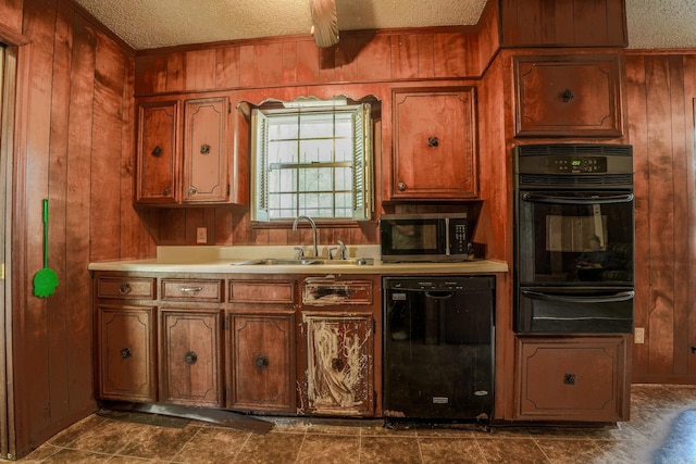 kitchen featuring black appliances, a warming drawer, a sink, wooden walls, and a textured ceiling