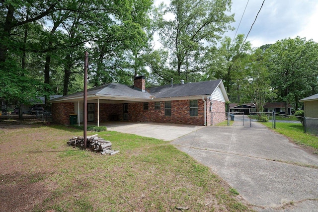 rear view of house featuring concrete driveway, a gate, brick siding, a chimney, and an attached carport