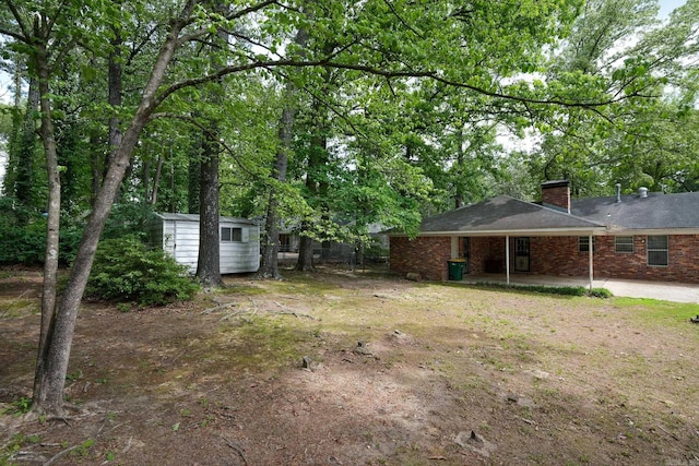 view of yard featuring an outbuilding, a storage unit, a carport, and a patio area