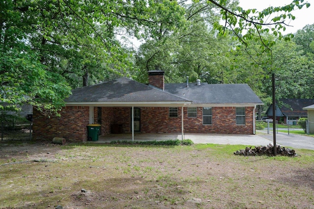 rear view of house with a chimney, fence, a patio, a shingled roof, and brick siding