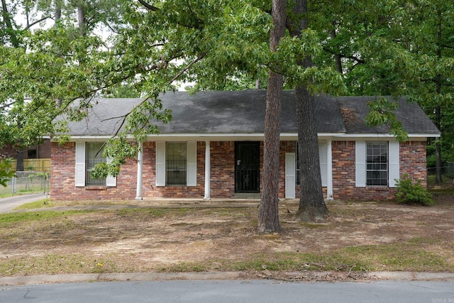 ranch-style house with brick siding, fence, and covered porch