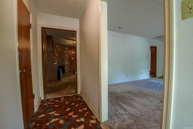 hallway featuring dark colored carpet and a textured ceiling