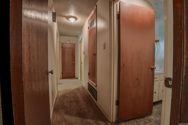 hallway with a textured ceiling and carpet floors