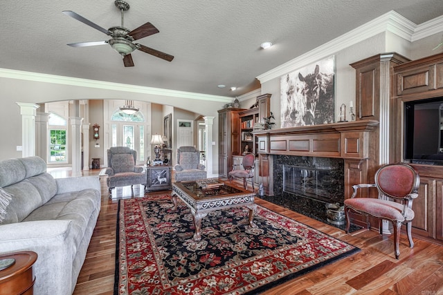 5 Granada Ln, Hot Springs Village, AR 71909 - living room featuring ornate columns, a fireplace, ceiling fan, wood finished floors, and crown molding