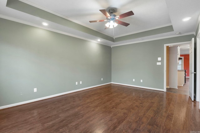 spare room featuring a raised ceiling, ceiling fan, dark wood-style floors, baseboards, and crown molding