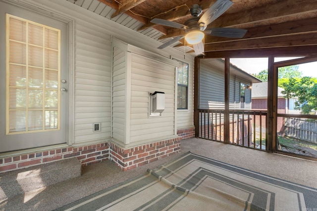 unfurnished sunroom featuring a ceiling fan, plenty of natural light, and beam ceiling