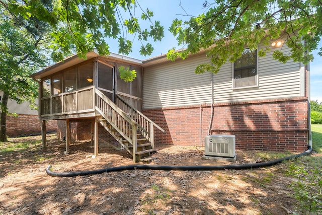 back of house featuring a sunroom, brick siding, stairway, and ac unit