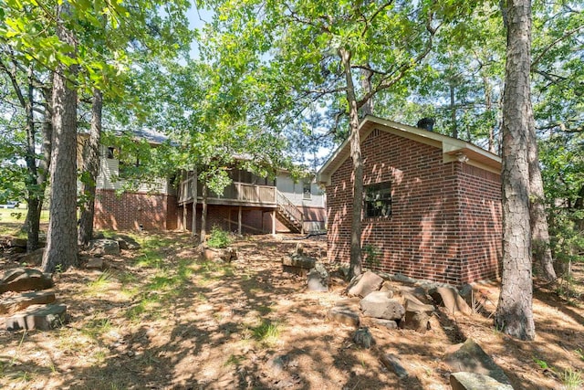 view of side of property featuring stairway, brick siding, and a sunroom