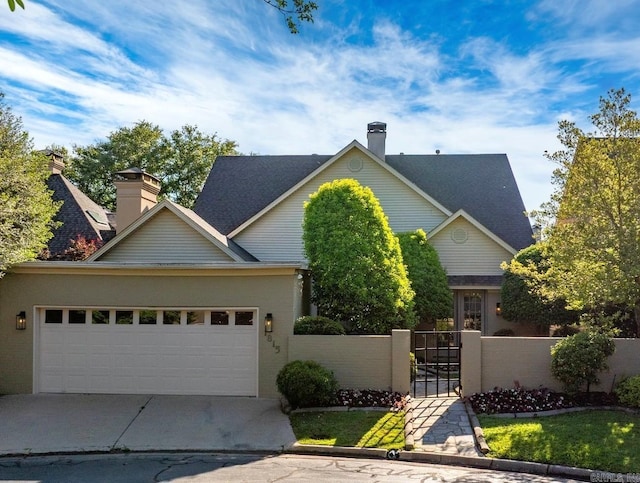 view of front facade with a chimney, a garage, a gate, and driveway