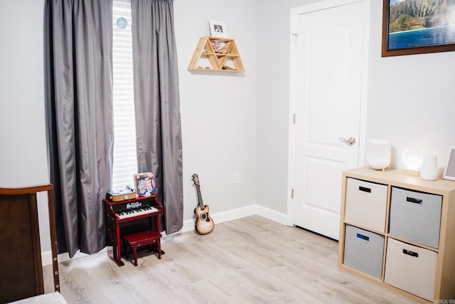 living area featuring light wood finished floors, baseboards, and healthy amount of natural light