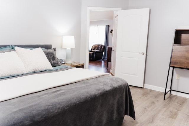 bedroom with light wood finished floors and baseboards