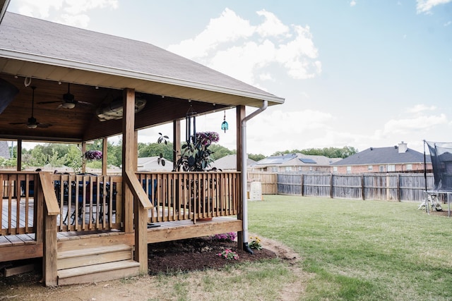 view of yard with a ceiling fan, a wooden deck, and a trampoline