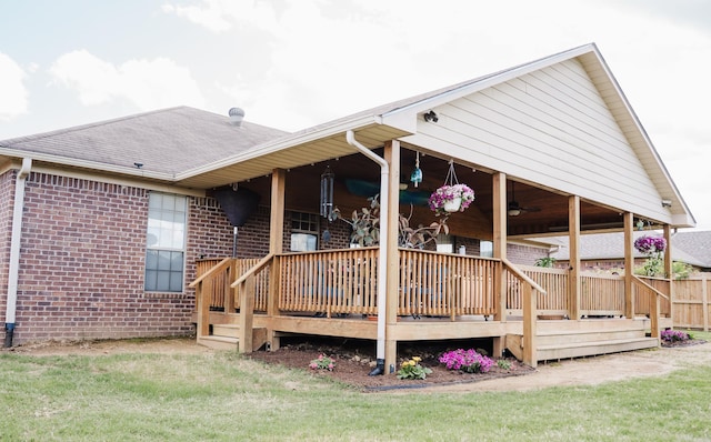 rear view of property featuring brick siding, ceiling fan, a deck, and a shingled roof