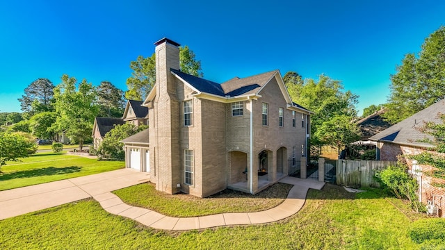 back of property with driveway, a chimney, brick siding, and an attached garage