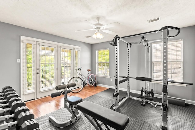 workout room with a ceiling fan, baseboards, wood finished floors, and a textured ceiling