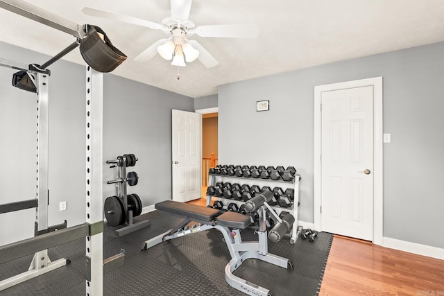 exercise room with a ceiling fan and baseboards