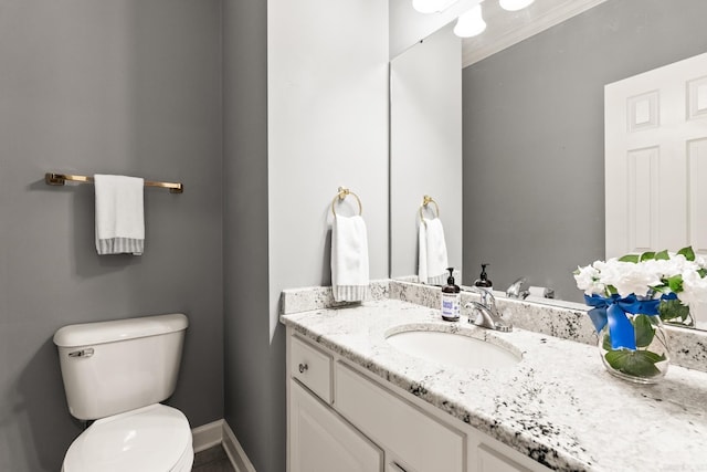 half bath with toilet, vanity, and baseboards