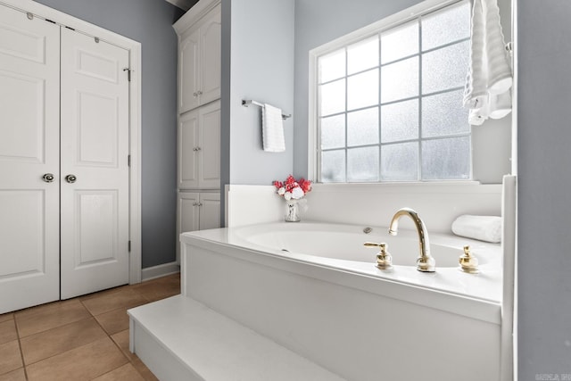 full bath with tile patterned flooring, a bath, and baseboards