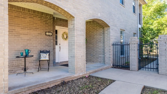entrance to property featuring brick siding, a gate, and fence