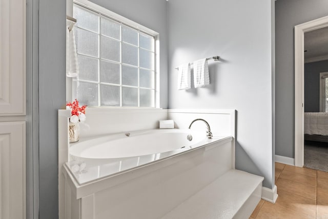 bathroom with tile patterned flooring, a garden tub, ensuite bath, and baseboards