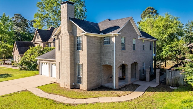 view of side of property with a chimney, driveway, brick siding, a garage, and roof with shingles