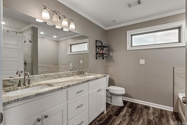 full bath featuring toilet, a tile shower, wood finished floors, baseboards, and double vanity
