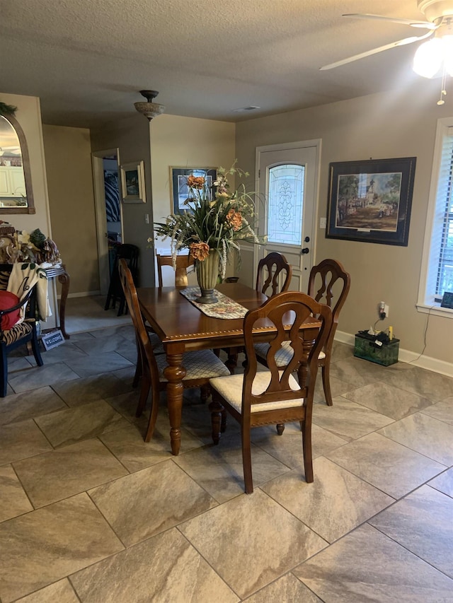 dining space with a ceiling fan, a textured ceiling, and baseboards
