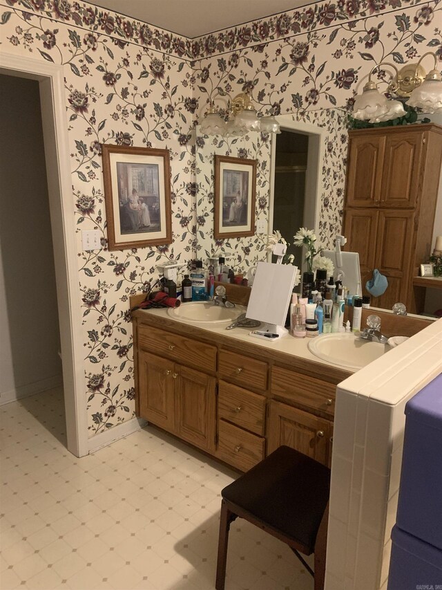 bathroom featuring wallpapered walls, tile patterned floors, baseboards, and double vanity