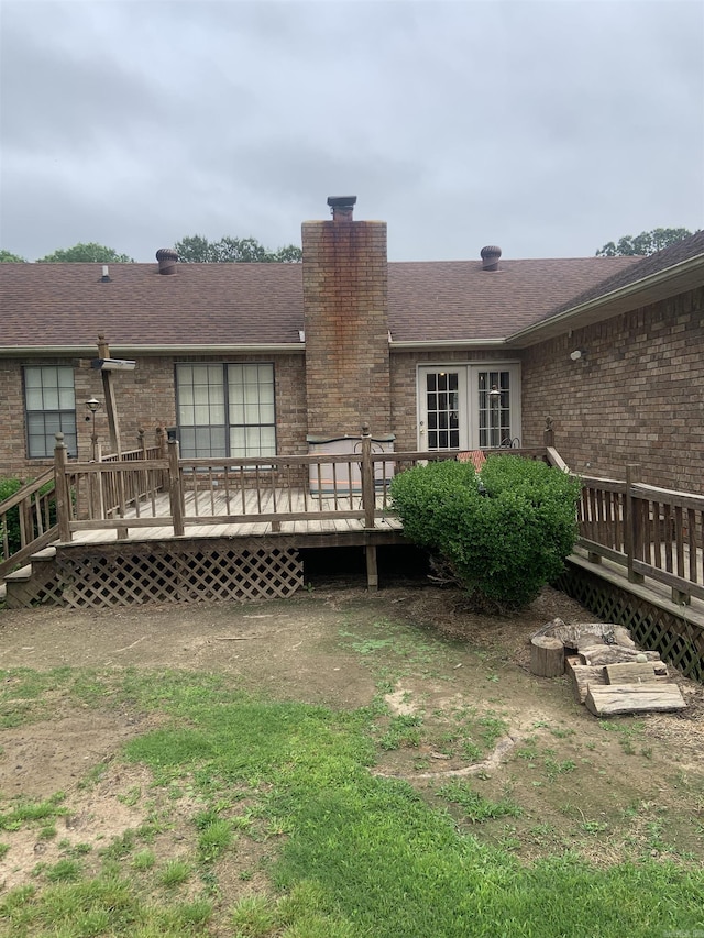 rear view of house featuring a chimney, a deck, brick siding, and a shingled roof