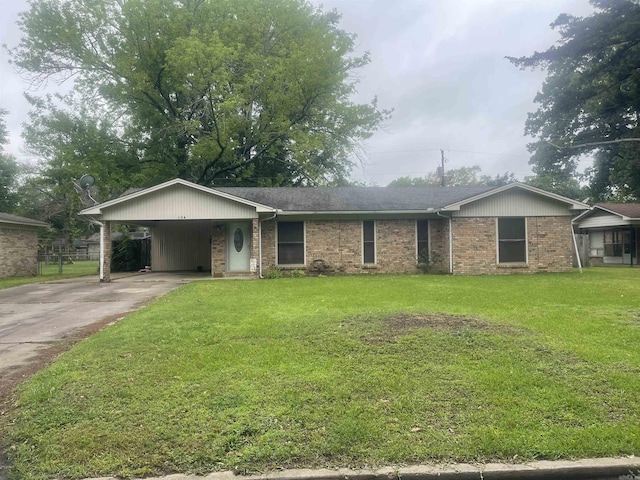 ranch-style home featuring driveway, brick siding, a front yard, and an attached carport