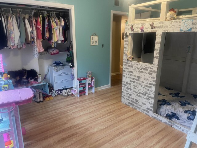 bedroom with wood finished floors, baseboards, and a closet