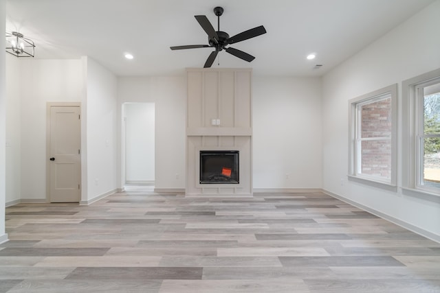 unfurnished living room with recessed lighting, light wood finished floors, a large fireplace, baseboards, and a ceiling fan