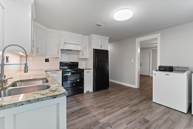 kitchen featuring black appliances, a sink, white cabinets, premium range hood, and backsplash