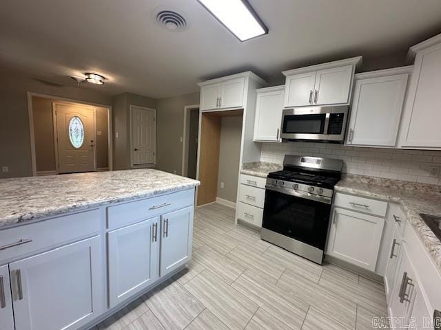 706 Scott St, Sheridan, AR 72150 - kitchen with appliances with stainless steel finishes, decorative backsplash, white cabinets, light stone countertops, and light tile patterned floors