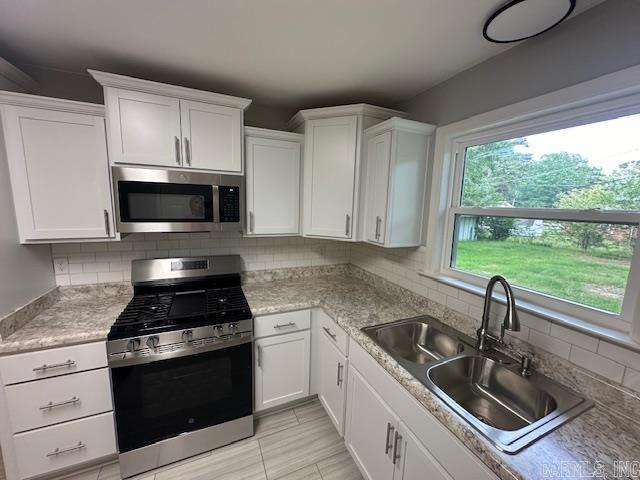706 Scott St, Sheridan, AR 72150 - kitchen featuring appliances with stainless steel finishes, a sink, white cabinets, and decorative backsplash