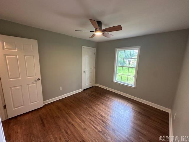 706 Scott St, Sheridan, AR 72150 - unfurnished bedroom featuring baseboards, dark wood-style flooring, and a ceiling fan