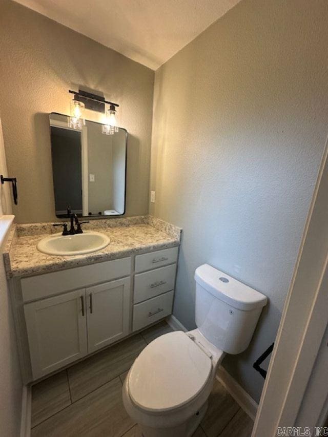 706 Scott St, Sheridan, AR 72150 - half bathroom featuring vanity, toilet, a textured wall, and wood finished floors